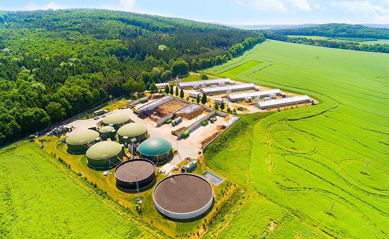 Biogas plant and farm in green fields.